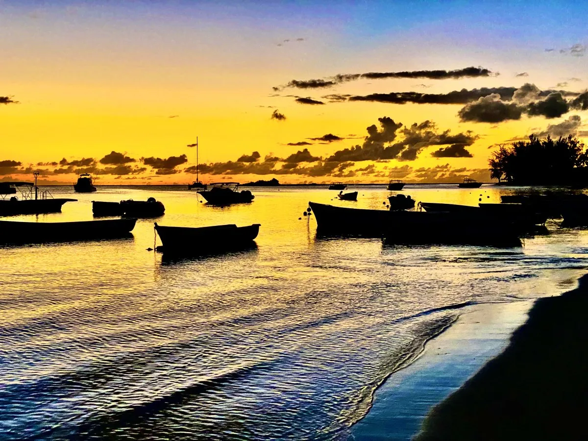 Yellow sunset with boat silhouettes at Mont Choisy Beach in Mauritius before dark