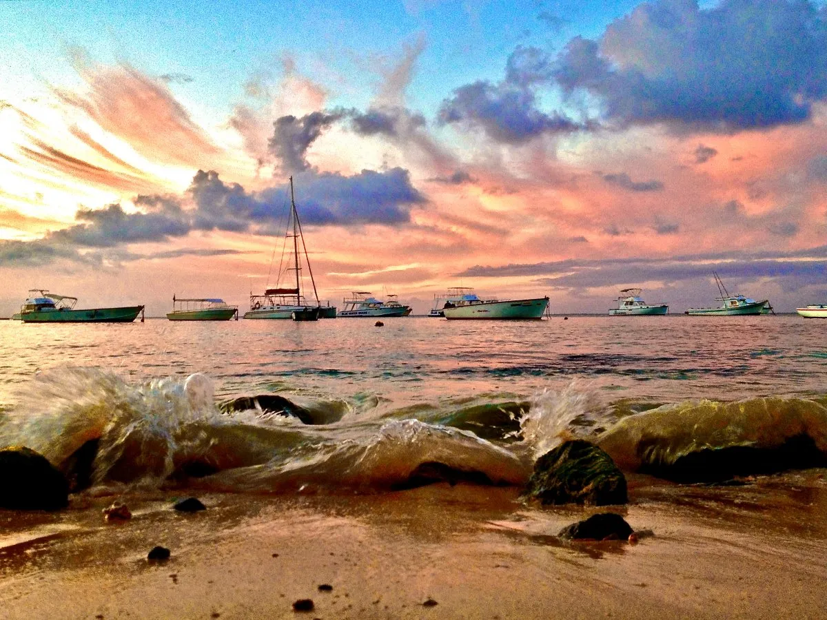 Sunset over Trou aux Biches beach with waves and boats in Mauritius