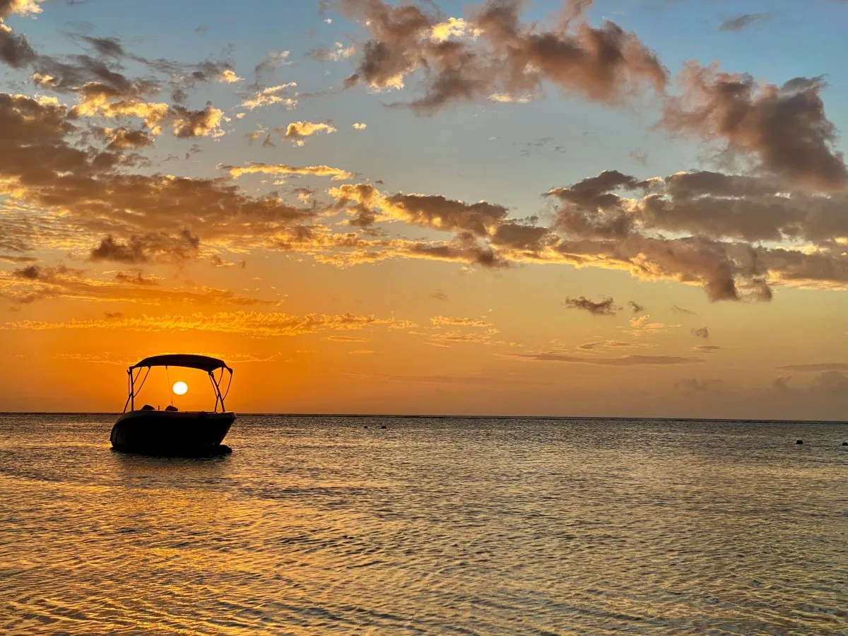 Sunset through boat silhouette over calm lagoon at Trou aux Biches, Mauritius