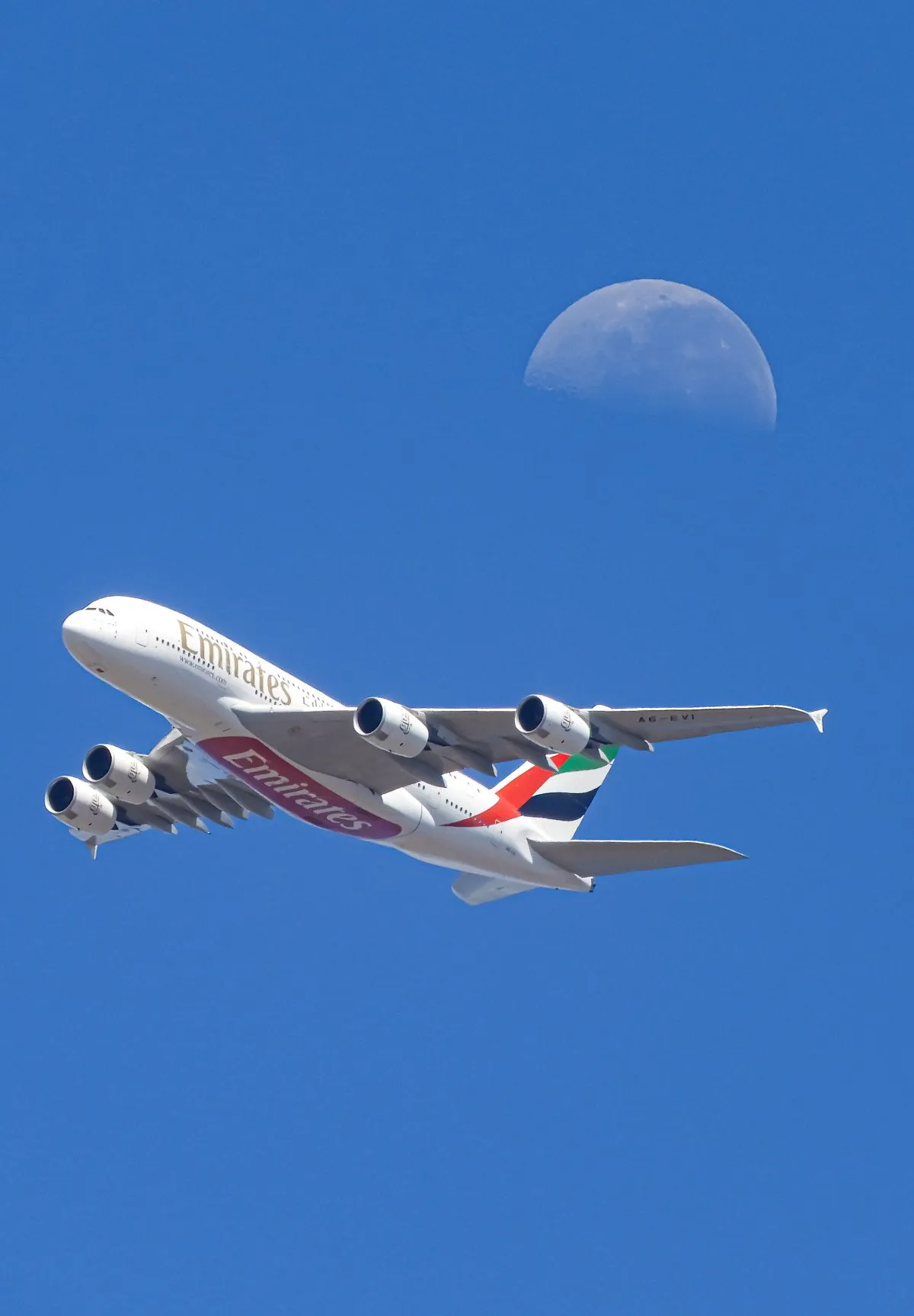Emirates A380 aircraft flying past the moon over Mauritius night sky