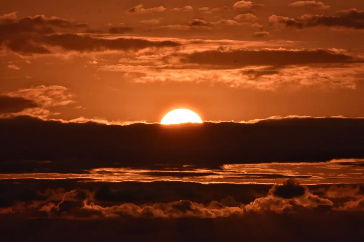 Orange sunset hidden behind clouds in Albion, Mauritius, creating a dramatic sky scene