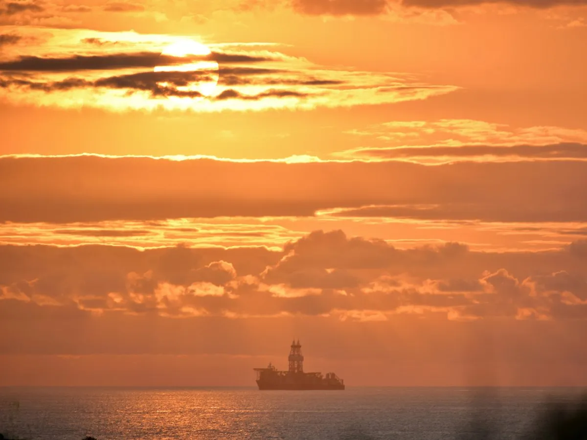 Silhouette of a supply vessel leaving Port Louis harbor under a sunset sky in Mauritius