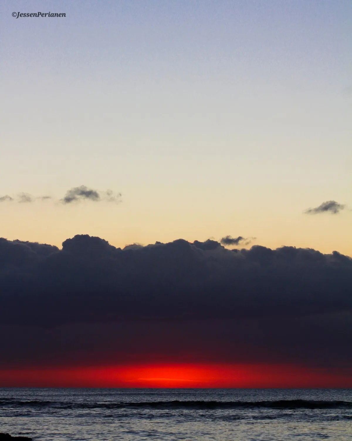 Reddish sunset below dark clouds at Pointe aux Piments beach in Mauritius
