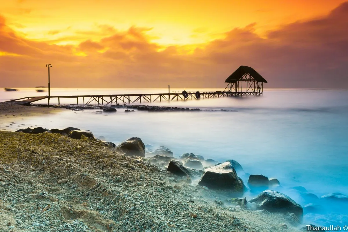 Long exposure shot of lagoon and jetty at Pointe aux Biches beach with vibrant sunset colors in Mauritius.