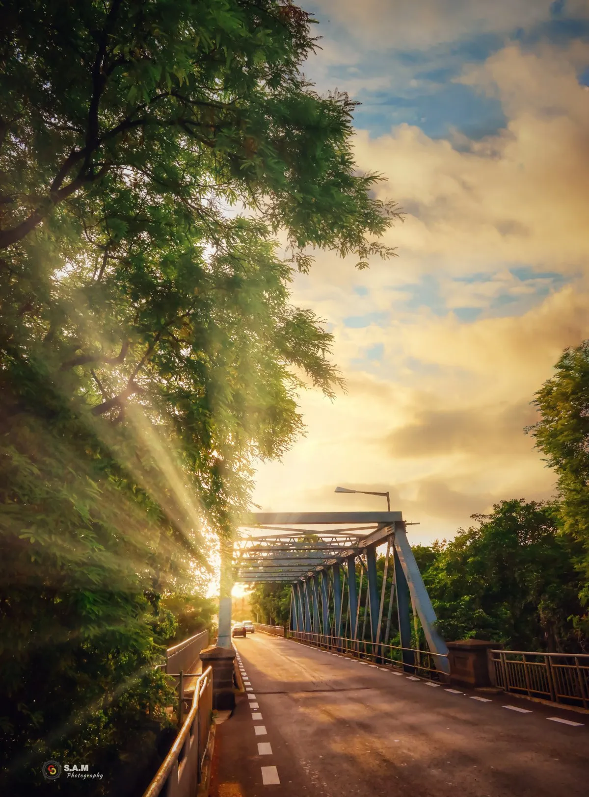 Sunlight shining through the bridge at Tamarin with road and trees in Mauritius during sunrise