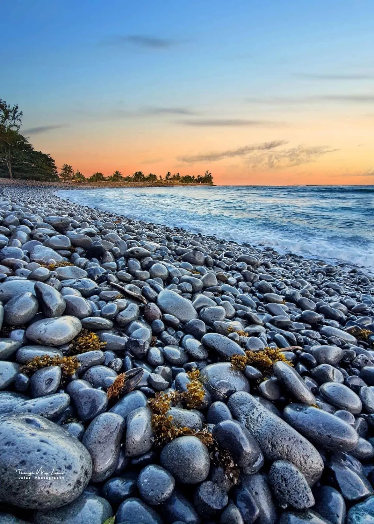 Riviere de Galets beach in Mauritius covered with black rounded wet pebbles at sunrise