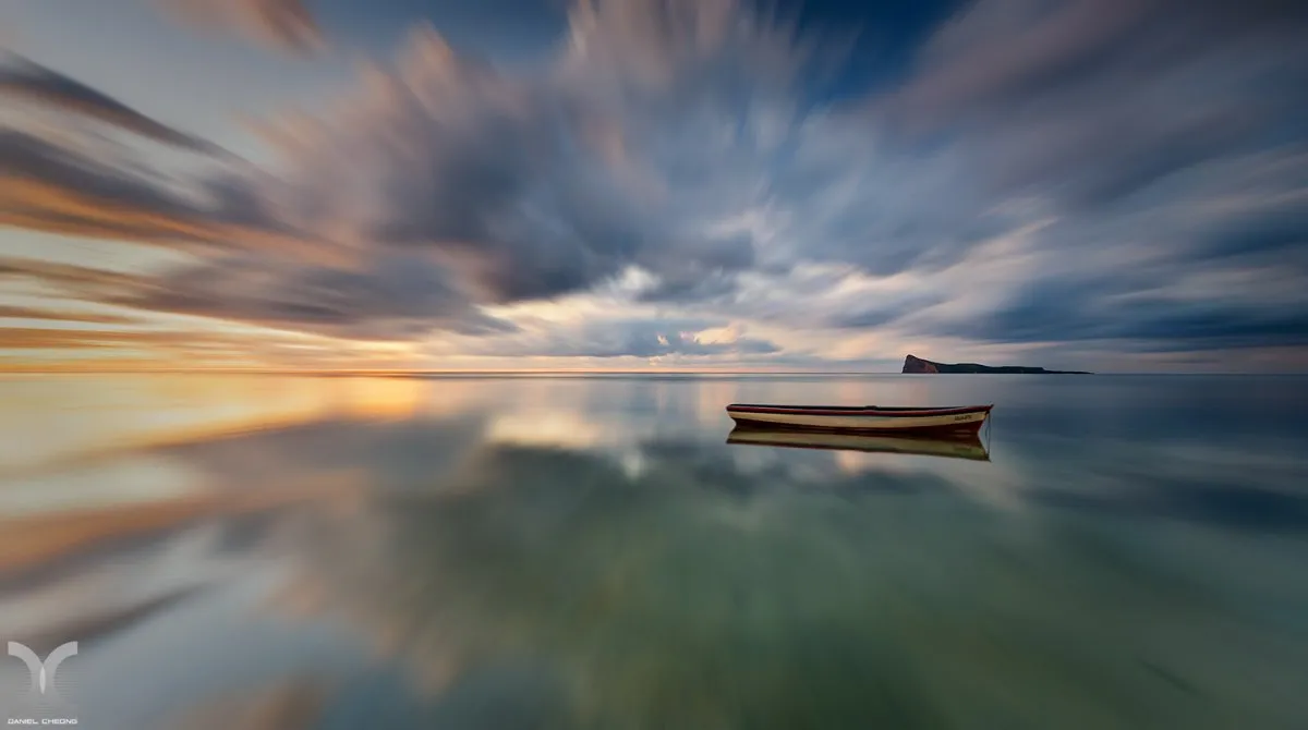 Long exposure photo of Pereybere Beach with clouds, sea, and a boat in Mauritius