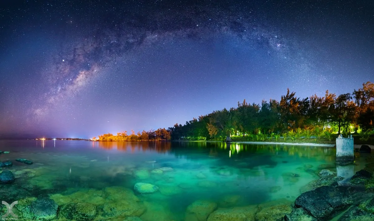 Milky Way glowing over the tranquil sea at Anse La Raie on the north coast of Mauritius