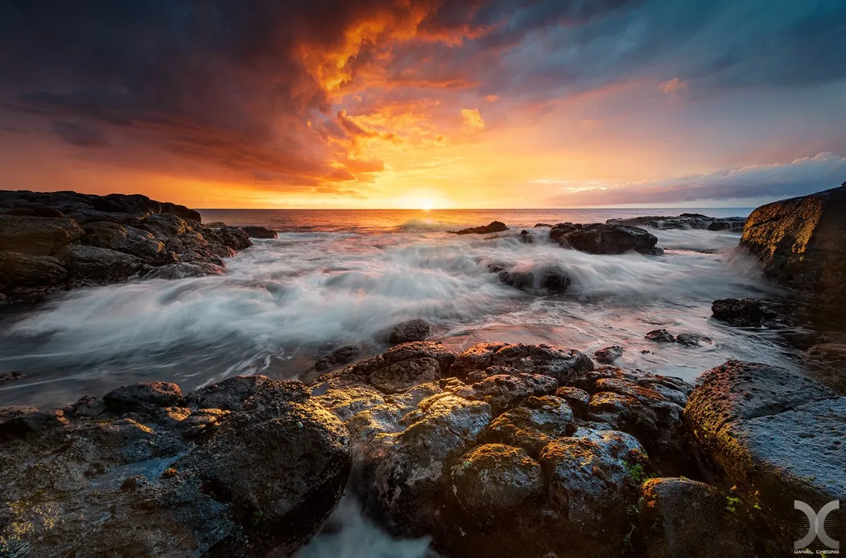 Dramatic sunset over rocky Albion beach with red clouds and glowing rocks in Mauritius