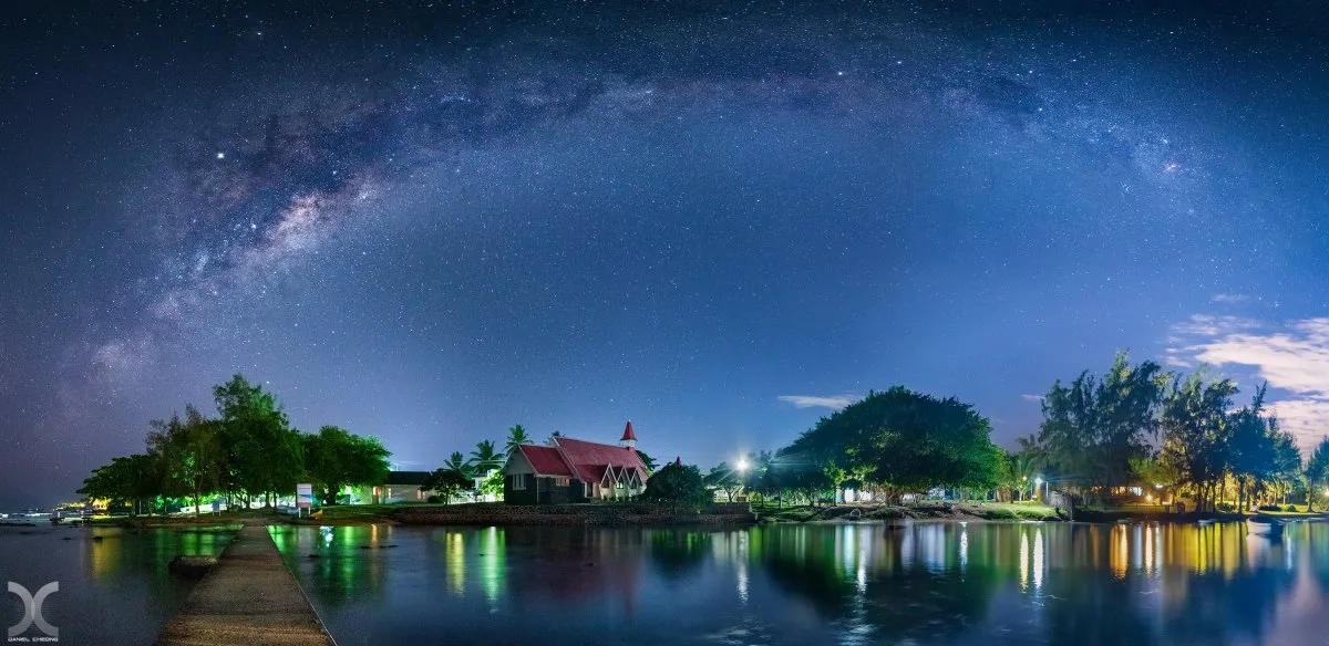 Night panorama of Milky Way above the red roof church at Cap Malheureux in Mauritius with sea reflections
