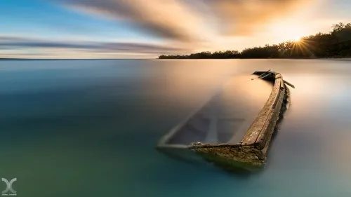 Amazing view of wrecked pirogue in lagoon at sunrise