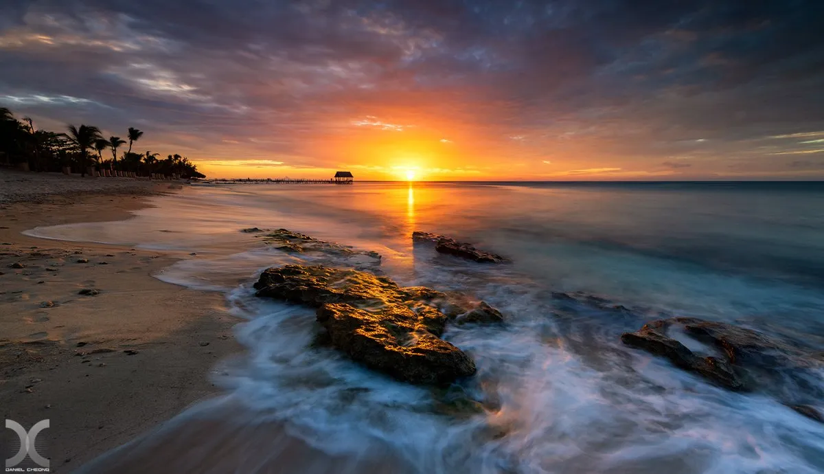 Sunset over Pointe aux Piments beach with filaos and coconut trees in Mauritius