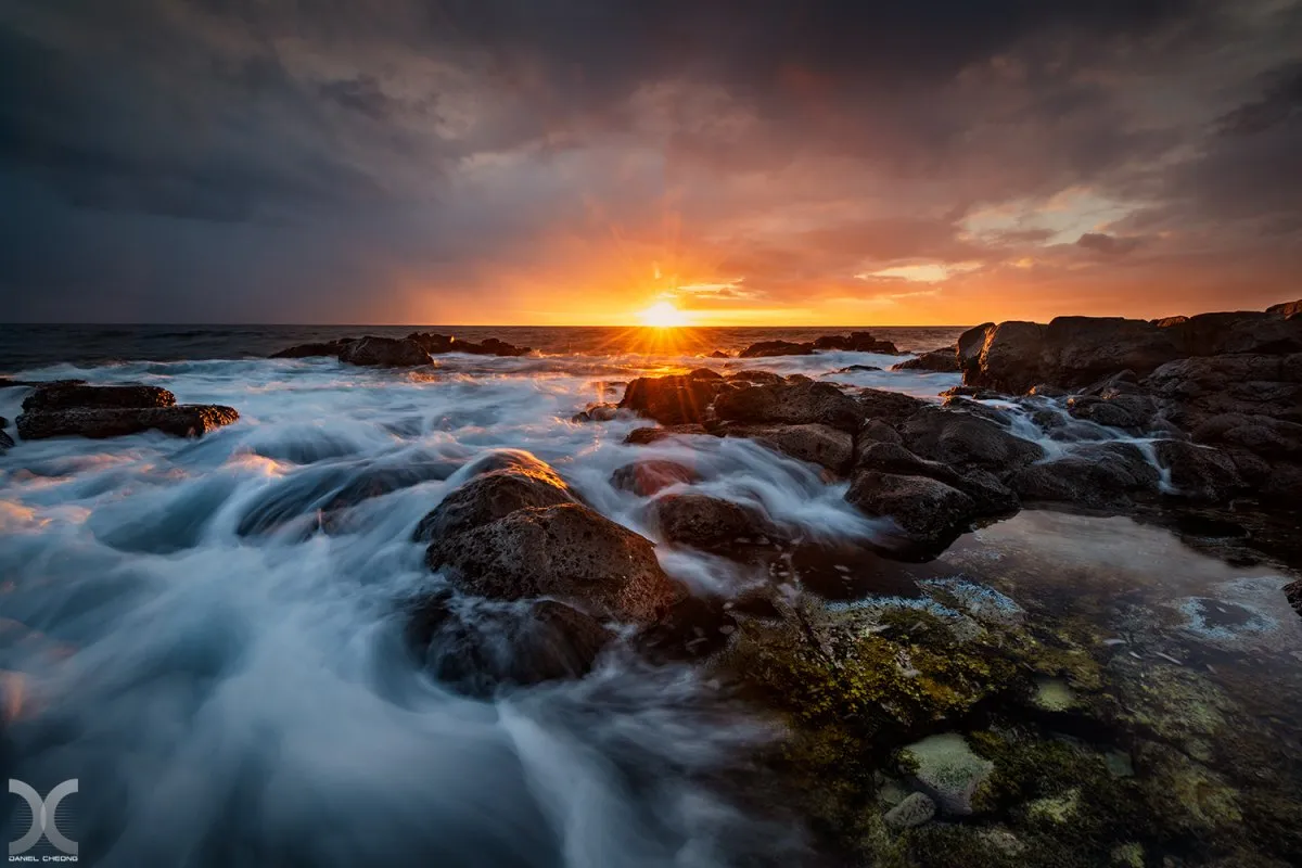 Sunset over Albion beach in Mauritius with dark clouds and volcanic rocks reflected in the sea