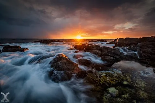 Seascape of Albion beach under dark clouds at sunset