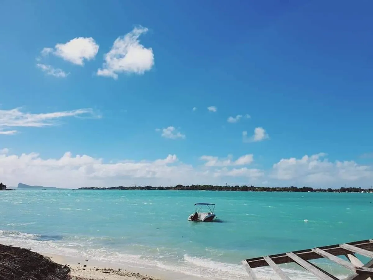 Boat floating in turquoise lagoon at Trou aux Biches beach, Mauritius on a sunny day