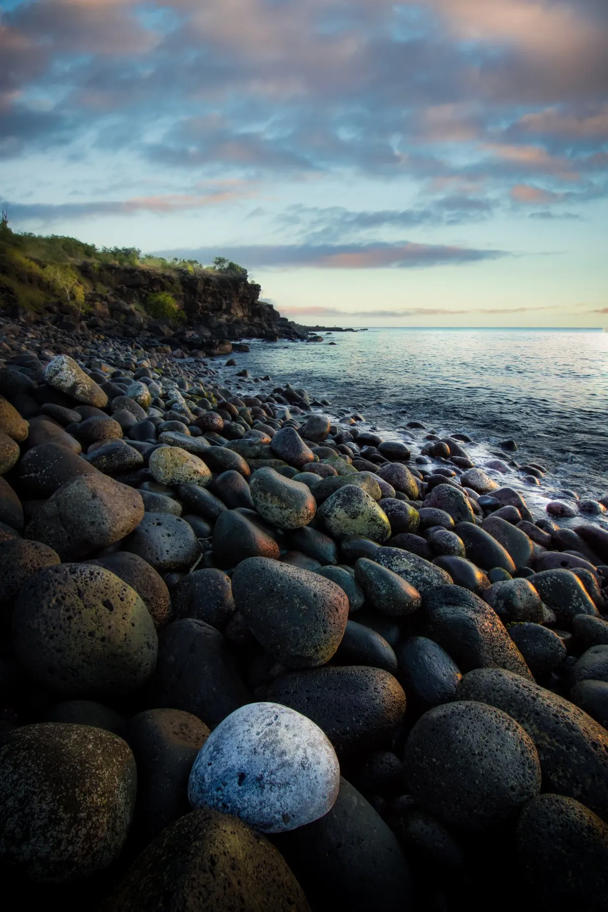 Colorful polished stones on a rocky beach with cliffs on the west coast of Mauritius