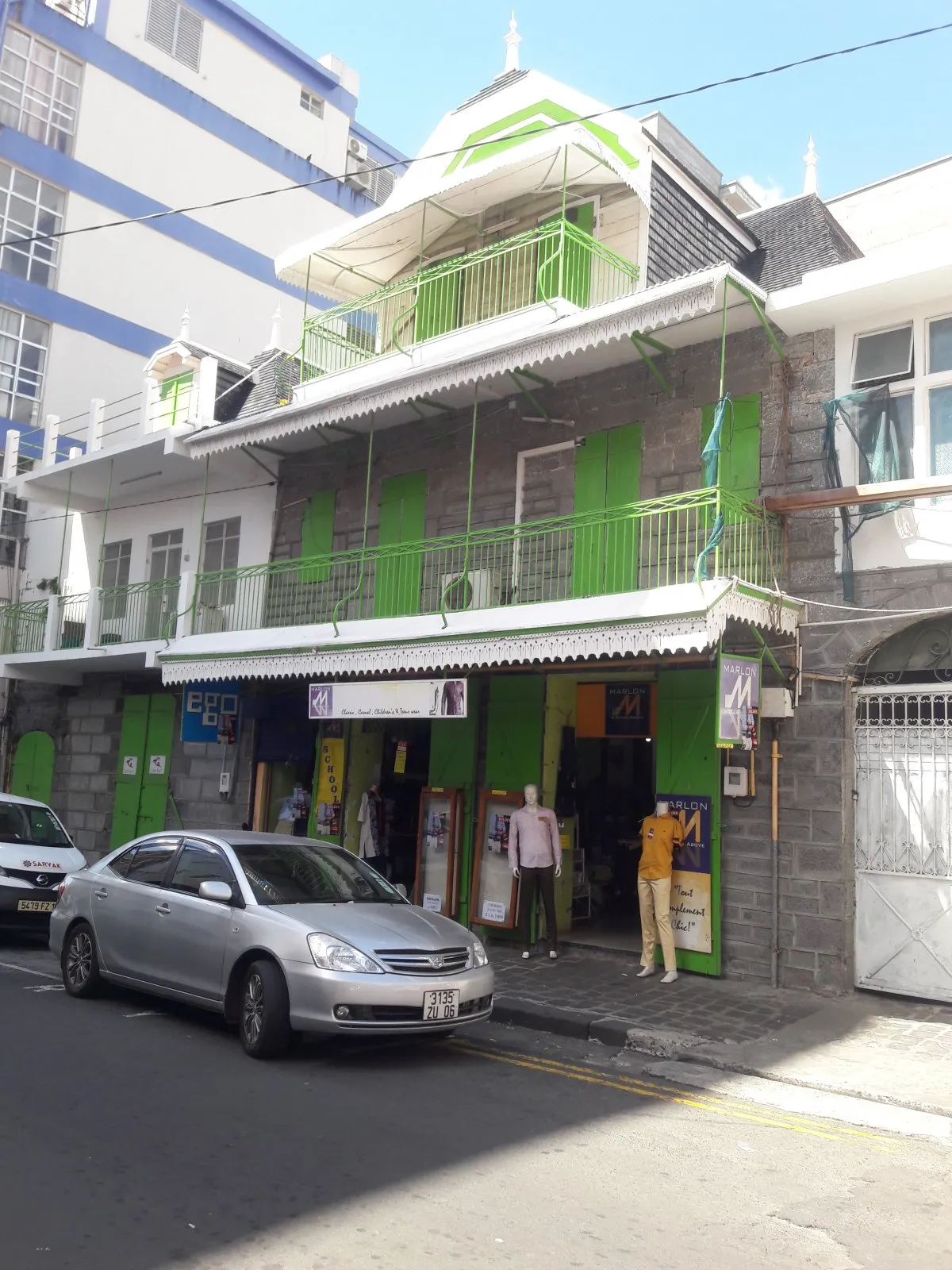 Colonial building housing a shop with vehicles outside in Port Louis, Mauritius