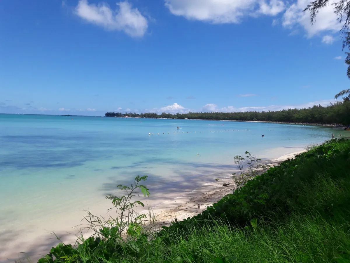 Mont Choisy beach in Mauritius with vibrant green grass lining the shore