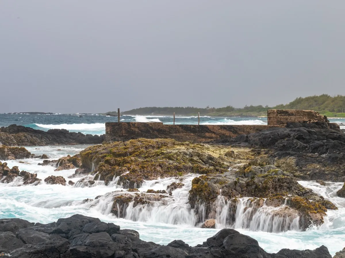 Sea water flowing down algae-covered rocks at La Cambuse beach in Mauritius