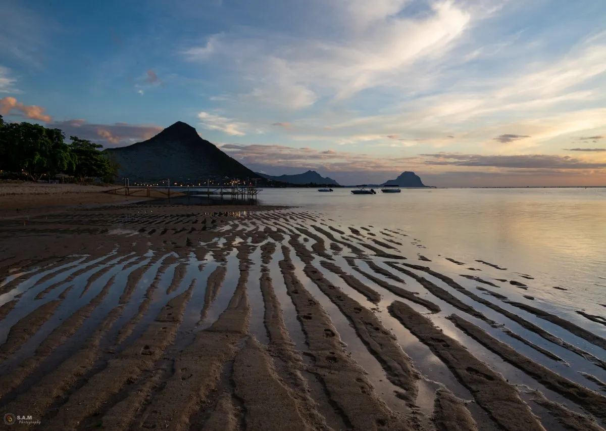 Low tide at Flic en Flac beach with La Tourelle Mountain in Mauritius under clear sky