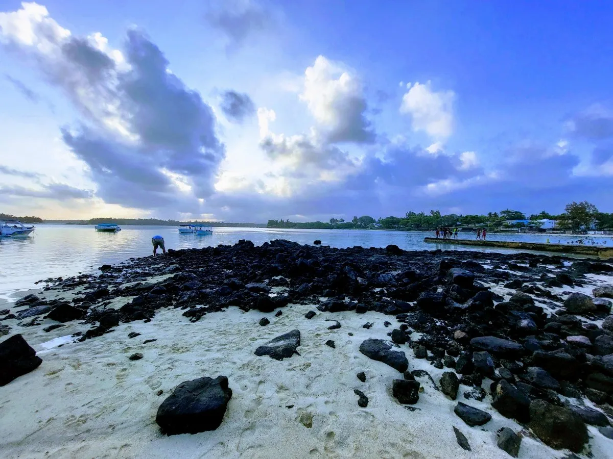 Rocky shoreline with blue sea and sky at Blue Bay Public Beach in Mauritius