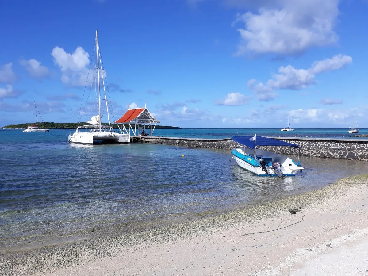 Jetty extending into clear waters by Preskil Beach Resort in Mahebourg, Mauritius under a bright sky