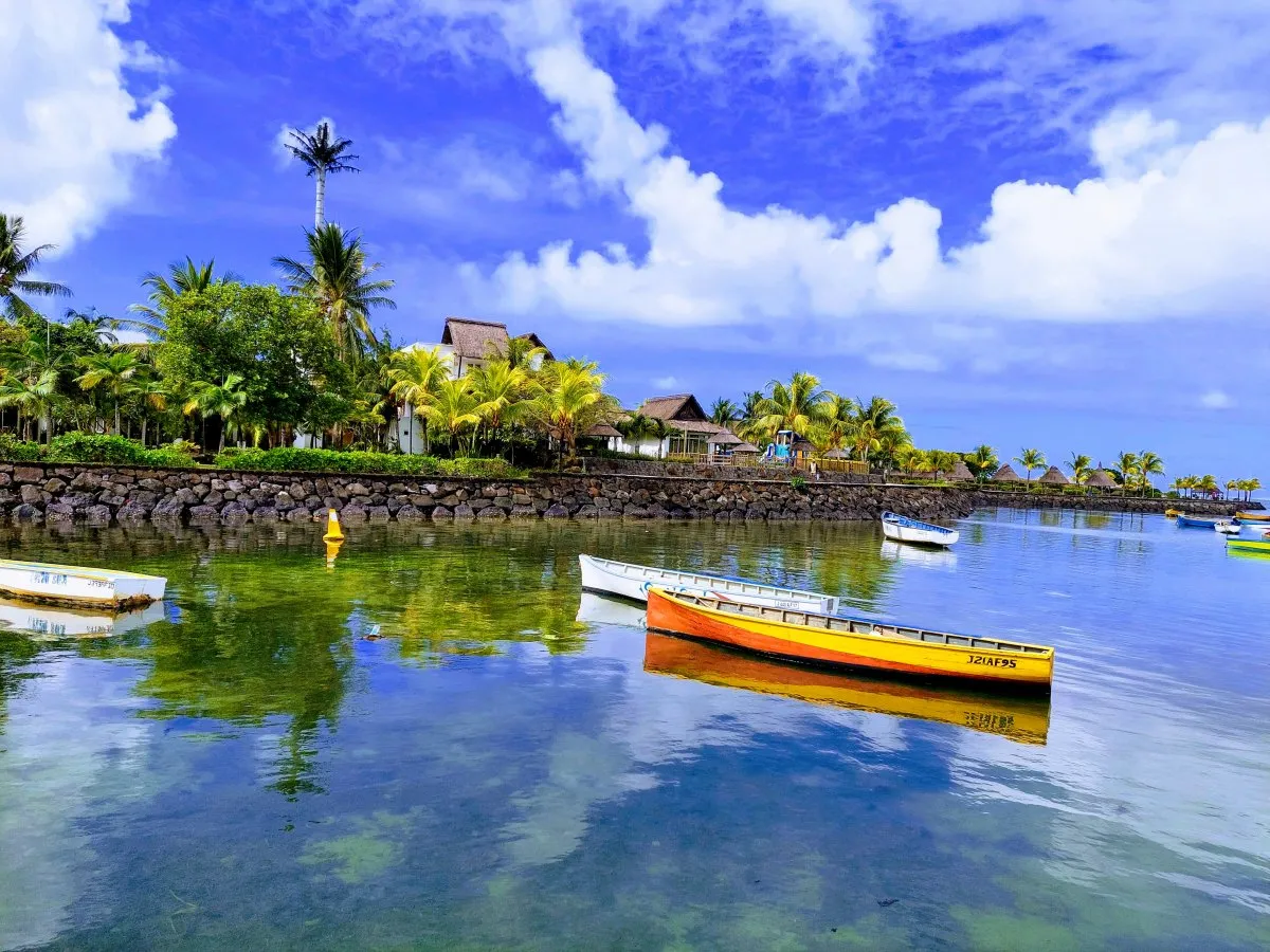 Fishing boats in lagoon near Laguna Hotel with tropical trees and mountains in Grande Riviere Sud Est, Mauritius