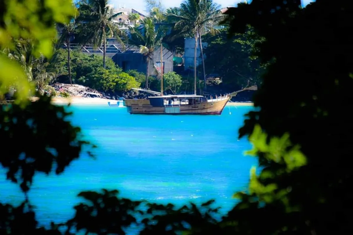 Old wooden sailboat moored in the turquoise waters of Trou d'Eau Douce bay, Mauritius