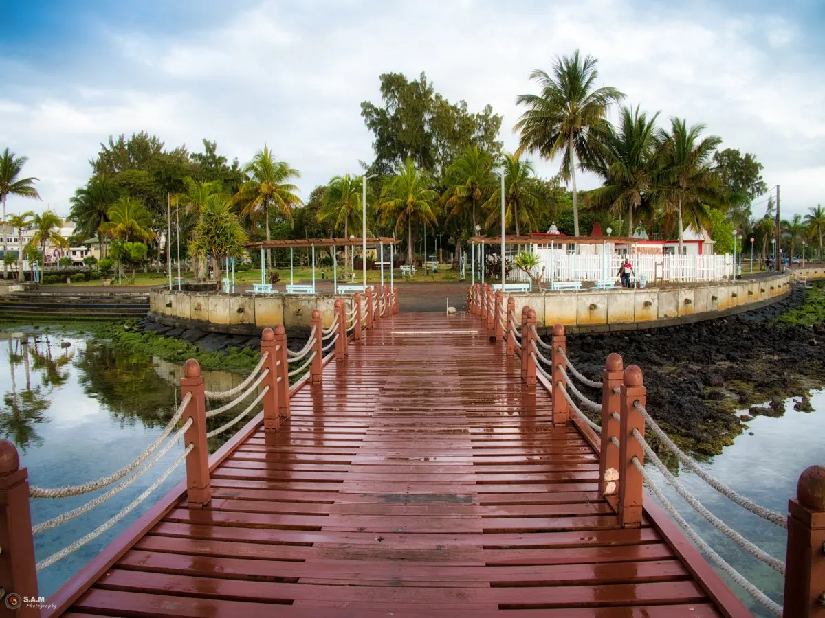 Wooden jetty over rocky shore at Mahebourg waterfront with palm trees in Mauritius