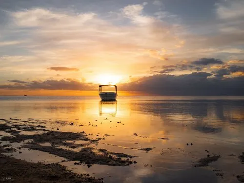 Sunset behind lonely boat at Flic en Flac beach