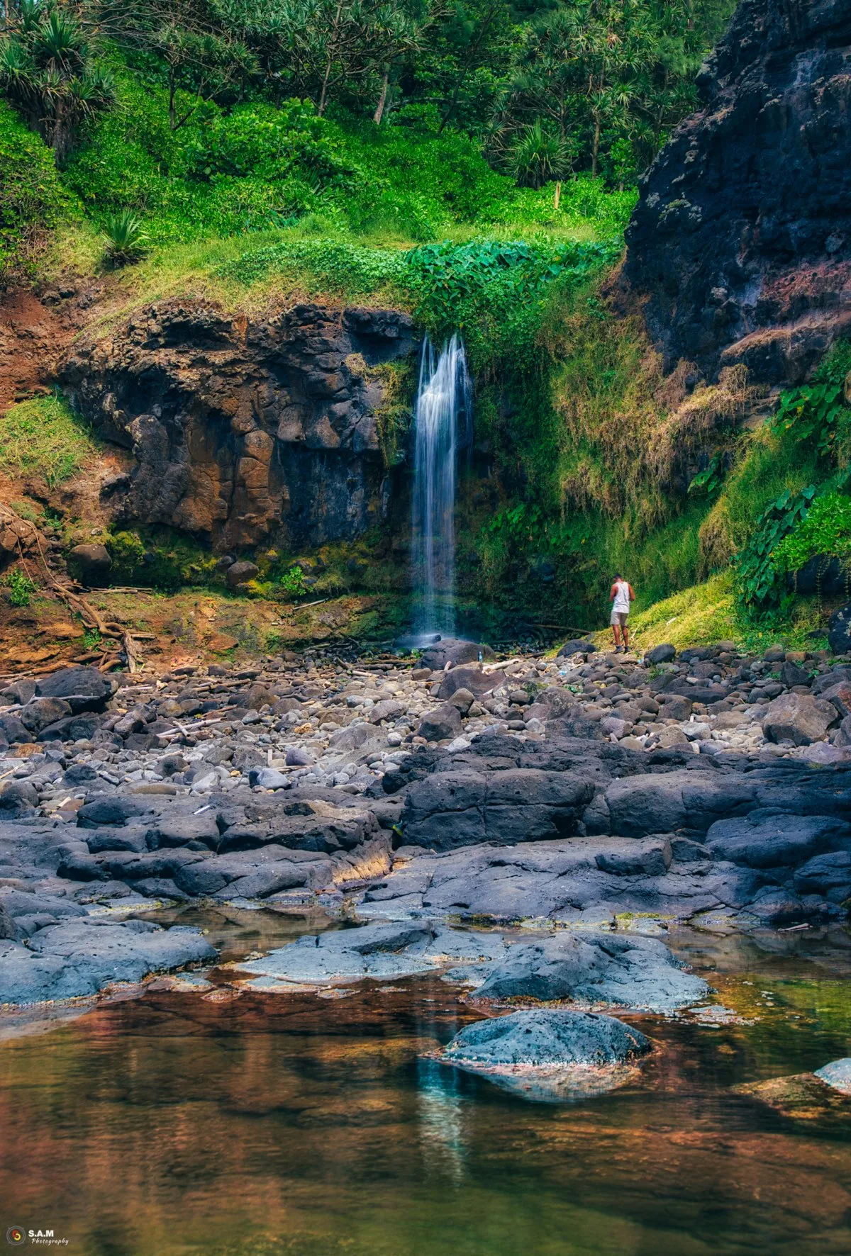 Man standing near a waterfall flowing into the sea at Gris Gris in Mauritius