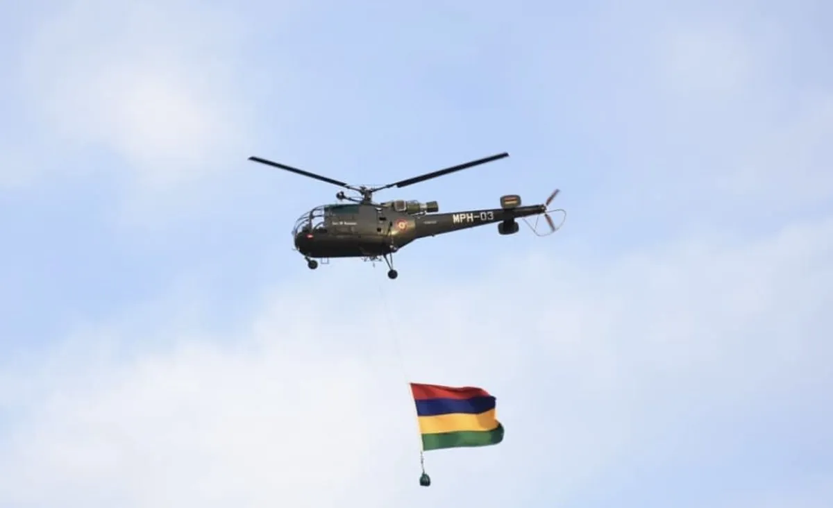 Military green SMF helicopter flying with the Mauritius flag against the sky