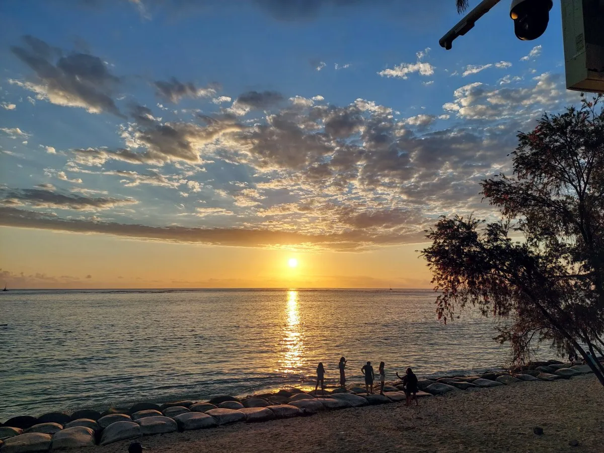 People silhouetted at Balaclava Beach during a stunning sunset in Mauritius with sun reflecting on the ocean