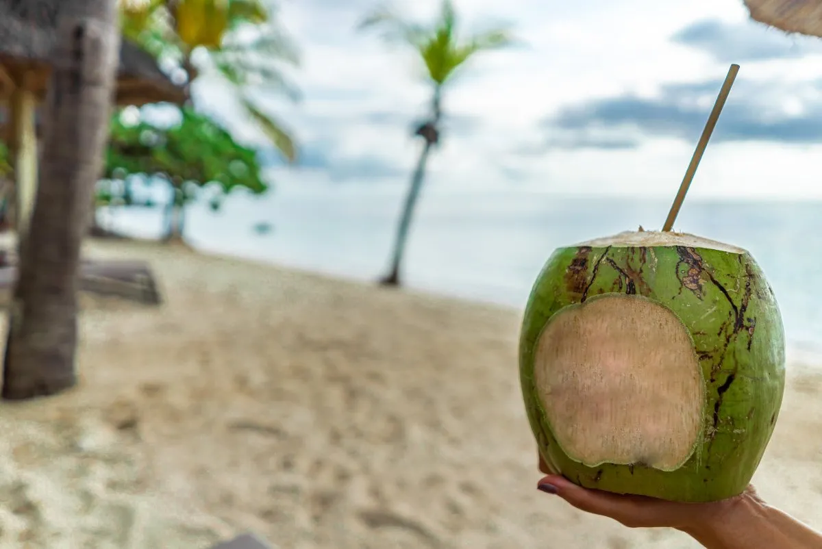 Refreshing coconut water with a straw on Le Paradis Beach in Mauritius