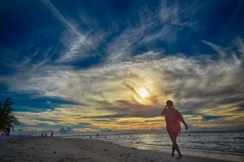 Woman walking on Flic en Flac beach before sunset