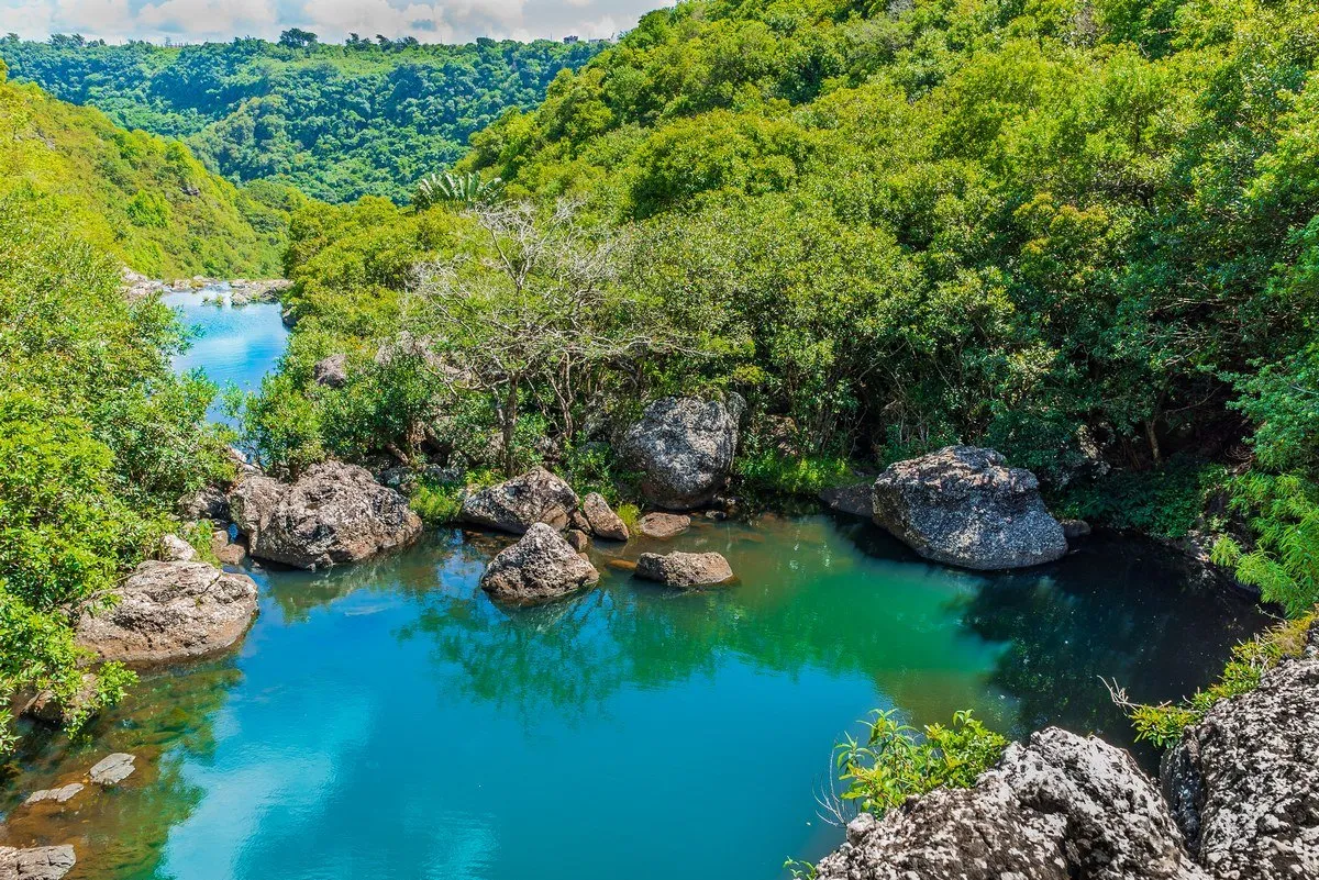 Natural swimming pool at Tamarind waterfall surrounded by lush forest at 7 Cascades in Mauritius