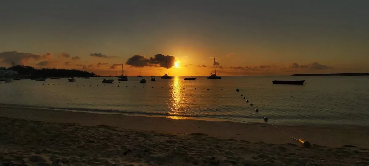Sunrise over Trou d'Eau Douce beach with fishing boats reflected on calm lagoon in Mauritius