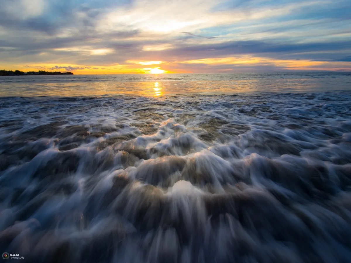Closeup of sea foam washing onto the shore at Tamarin Beach in Mauritius during sunset