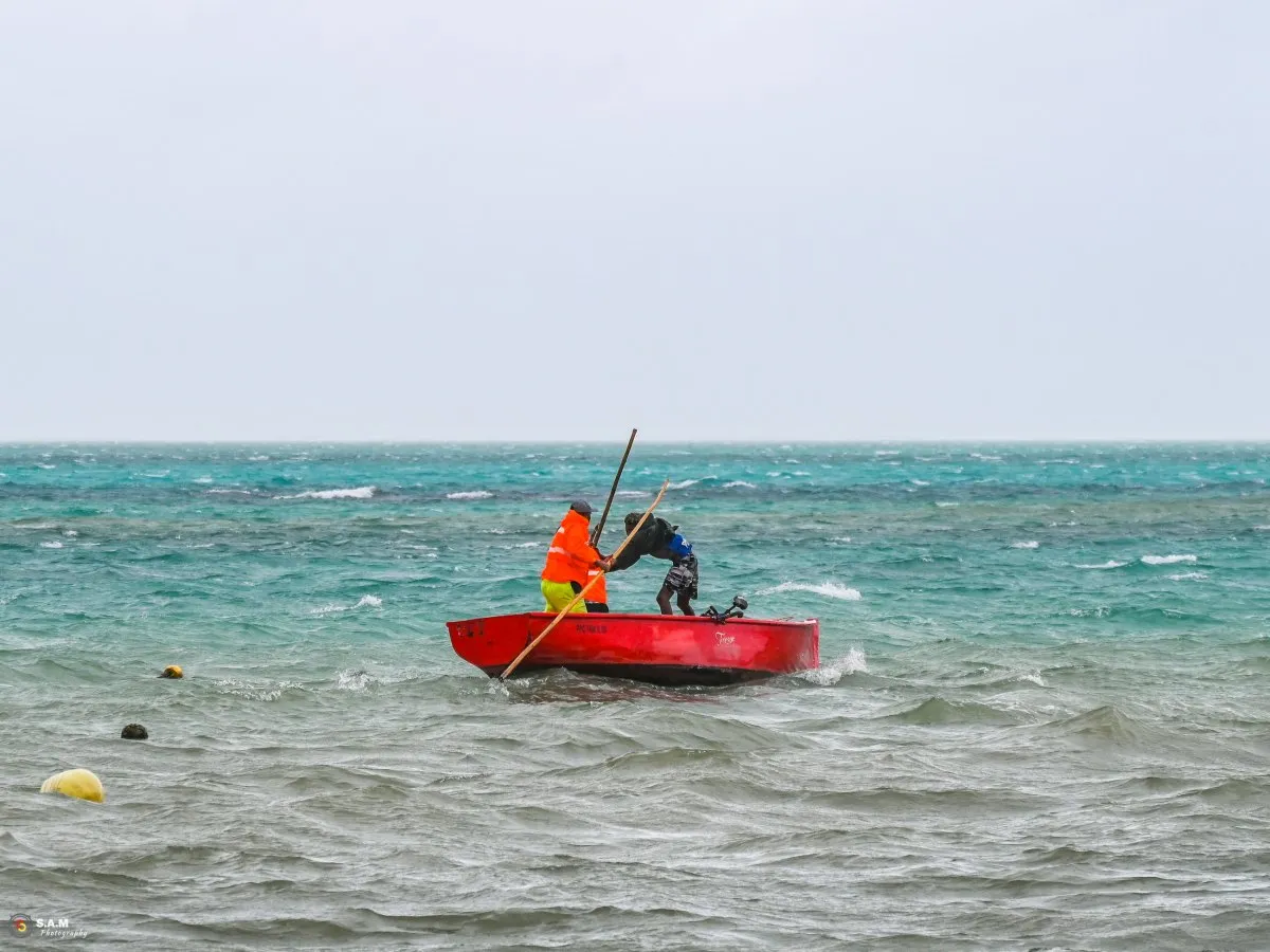 Two fishermen struggling with their boat in rough seas near Mahebourg, Mauritius.