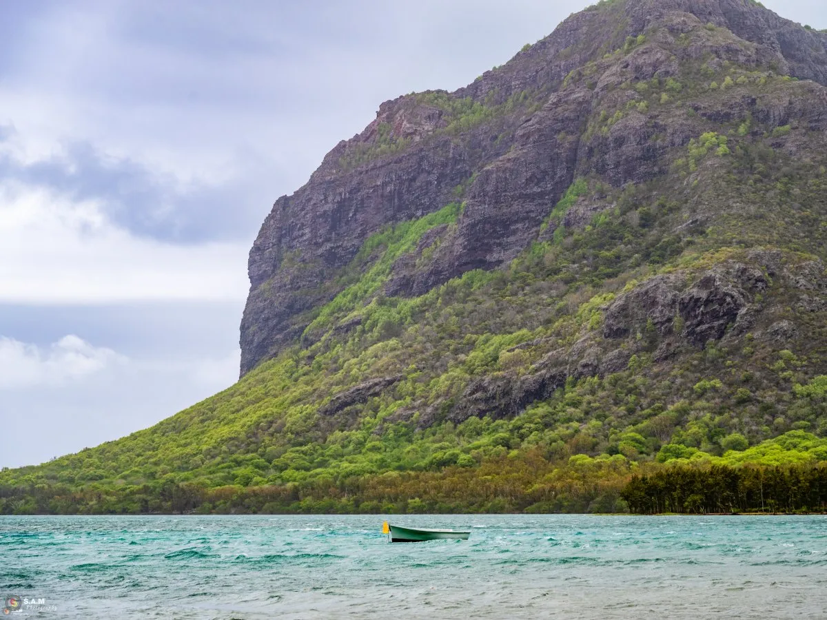 Traditional pirogue boat near lush Le Morne Mountain in Mauritius