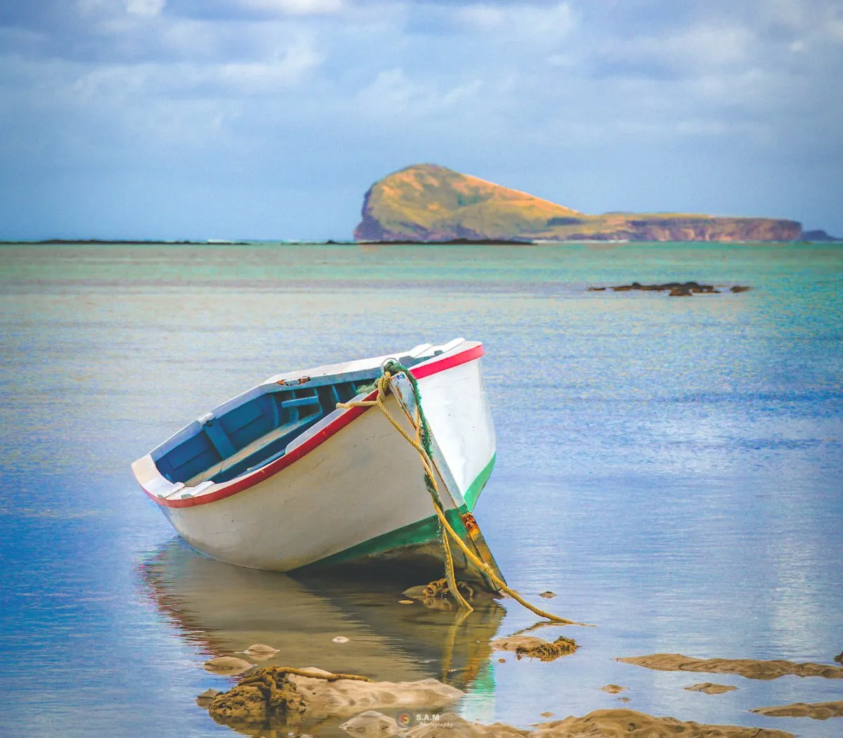 Fisherman's boat tied at Grand Gaube bay with Coin de Mire island in the distance in Mauritius