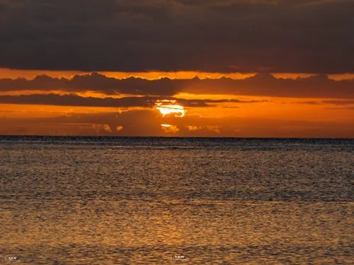 Sunset hiding behind clouds before vanishing behind the sea at Souillac