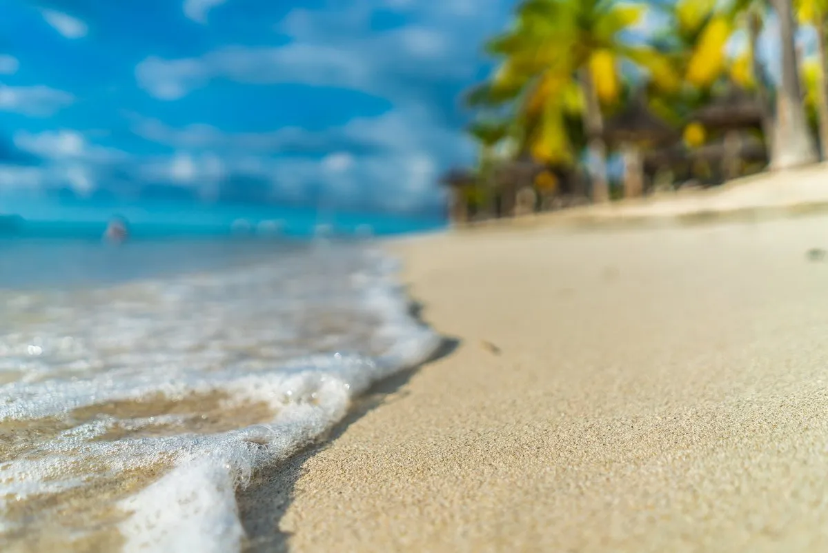 Calm sea waves gently hitting the golden sandy beach in Mauritius under clear skies