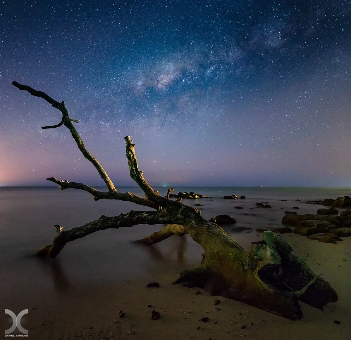 Long exposure of Milky Way over driftwood on Tamarin Beach, Mauritius with starry night sky