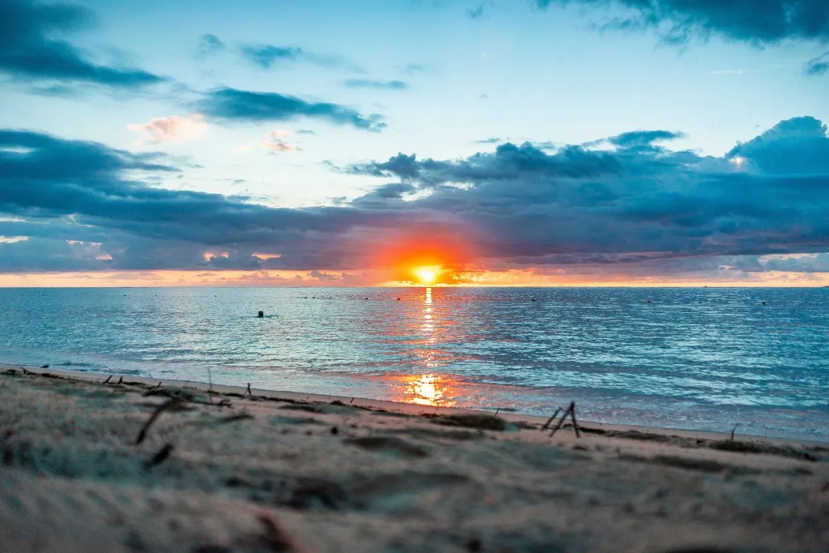 Reddish sunset over a peaceful beach lagoon with blue and grey sky in Mauritius