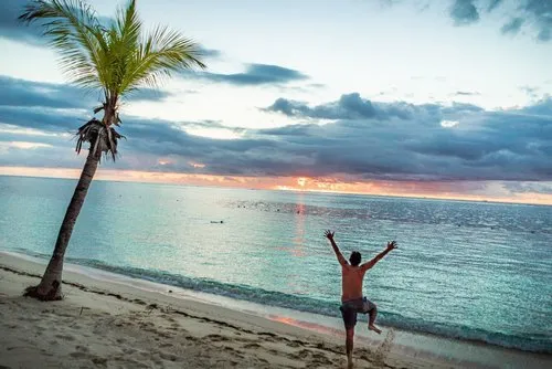 Happy man on secluded beach during sunset