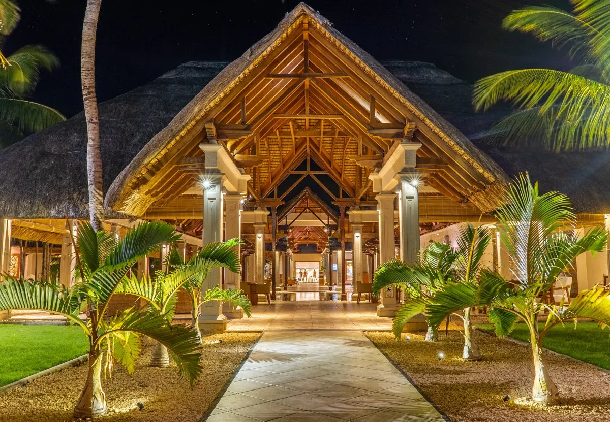 Night view of illuminated pathway and shops with thatched roofs at Le Paradis Hotel in Mauritius