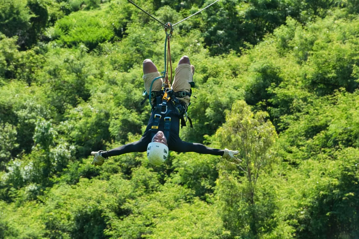 Person sliding upside down on zip line at Casela Nature Park in Mauritius.