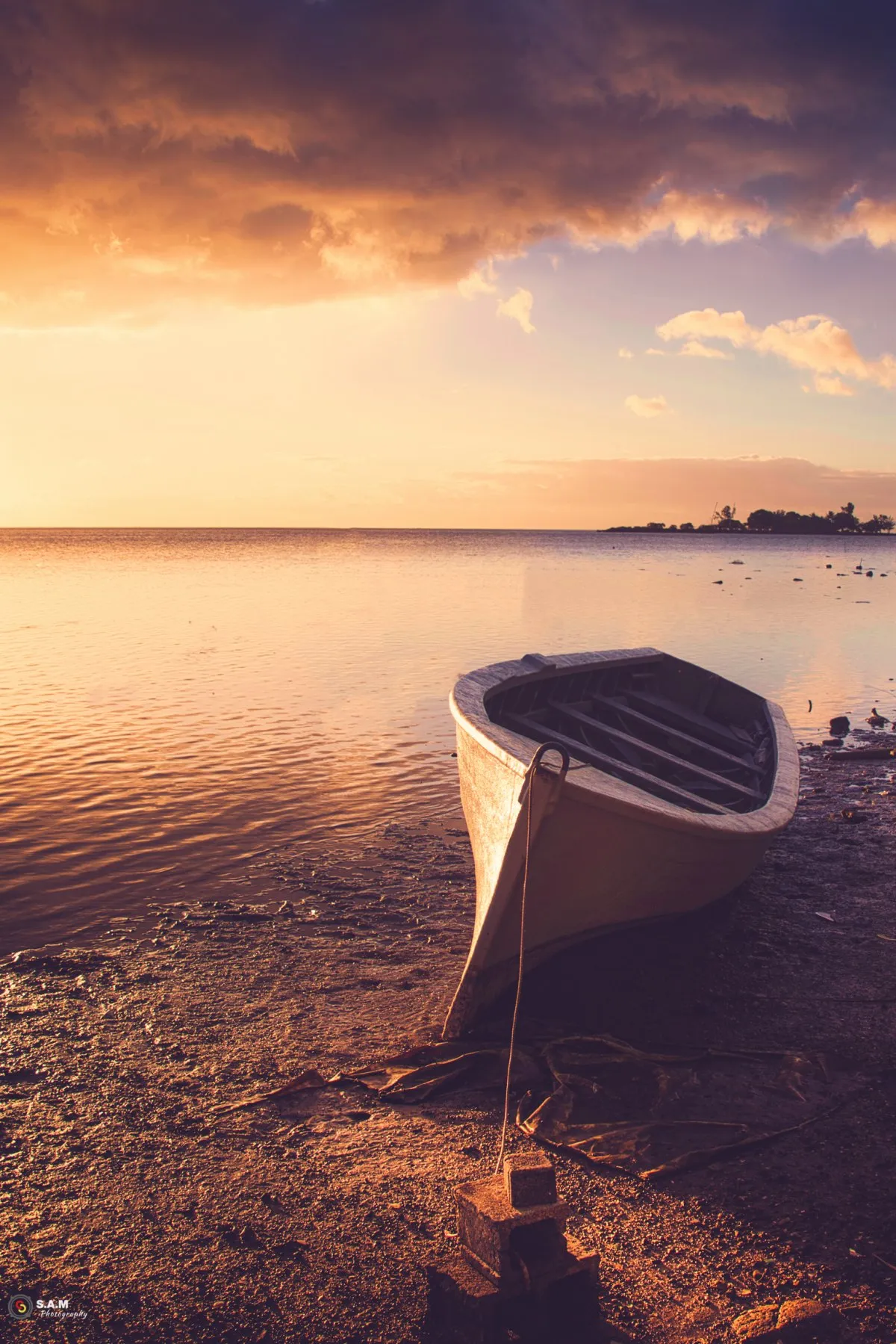 Fishing pirogue berthed on the sandy beach of Case Noyale village in Mauritius under cloudy skies