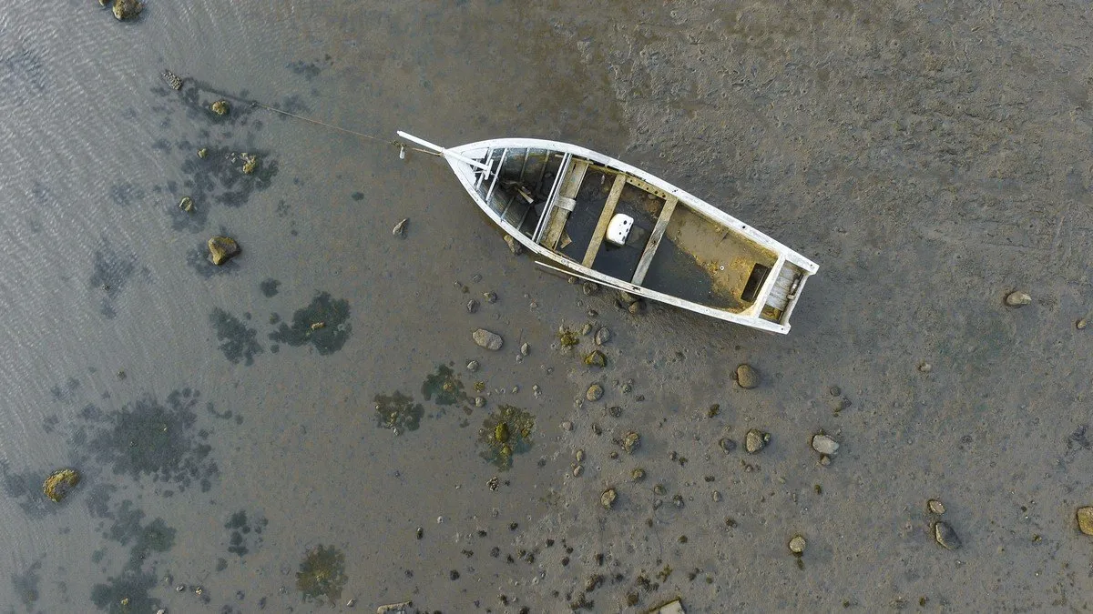 Aerial shot of a wrecked wooden boat on a muddy beach at low tide in Case Noyale, Mauritius